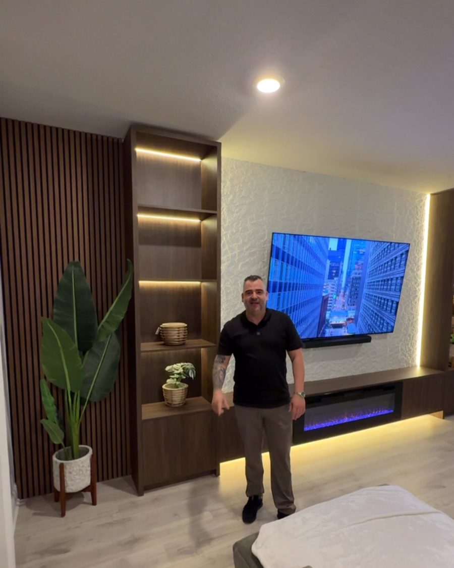 Santiago, owner of SG Home Designs, in front of a finished media wall