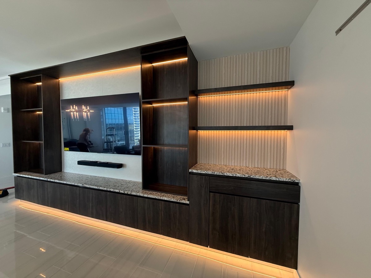 Full-width wall unit with warm lit floating shelves